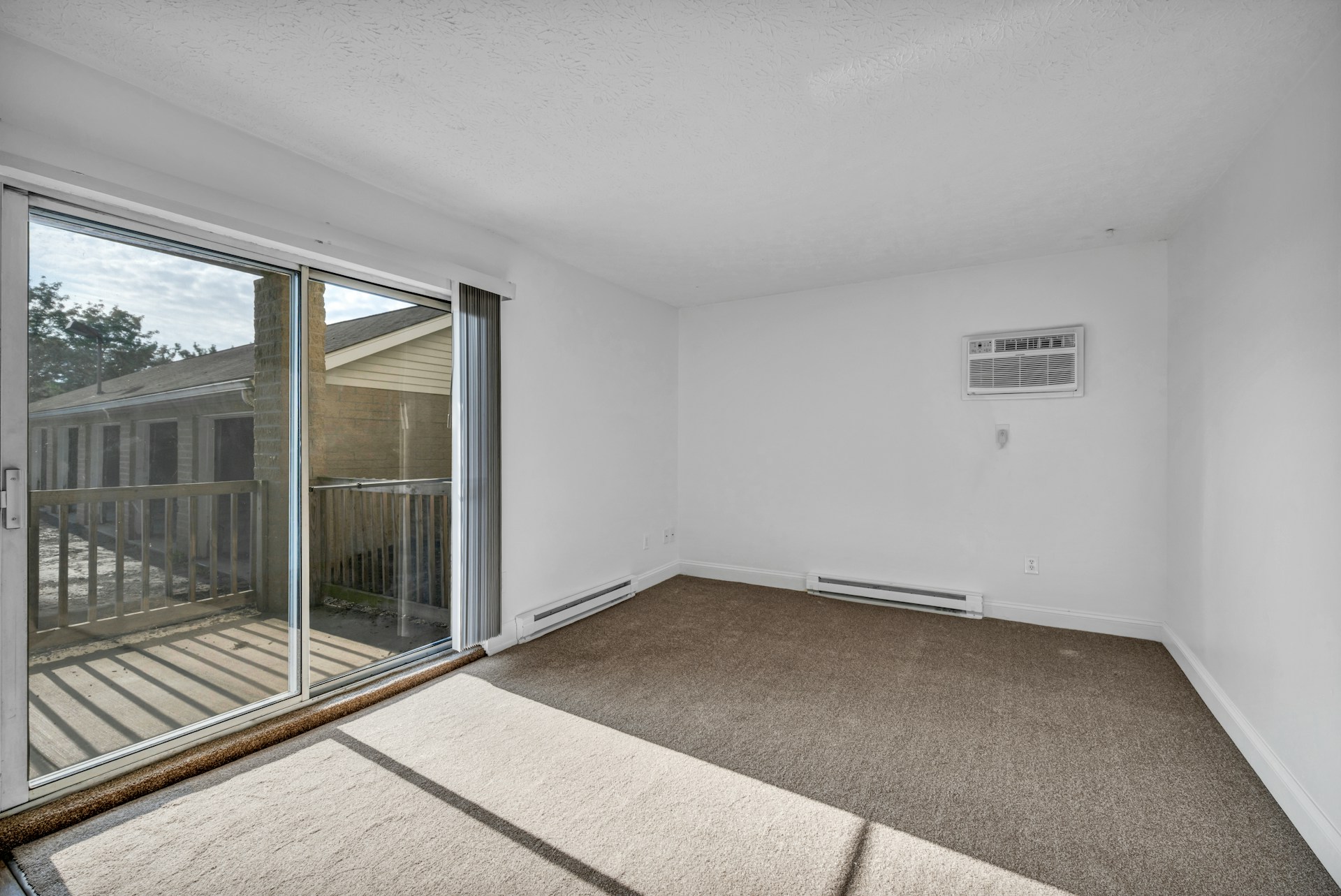 Empty room with brown carpet and a sliding glass door, the kind of flooring wear and tear disputes are about.