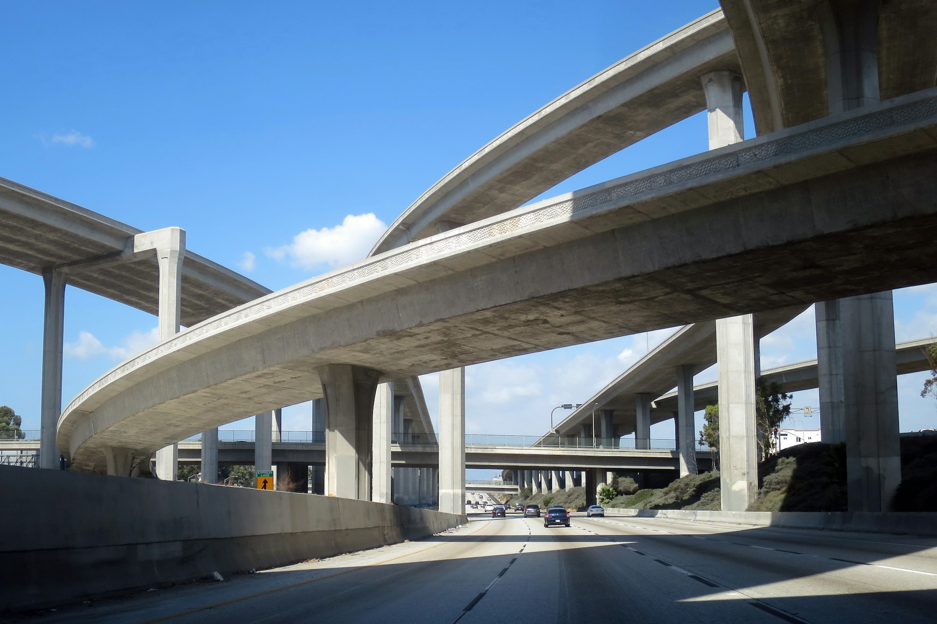 Los Angeles freeway interchange seen from the road, with concrete ramps curving overhead.