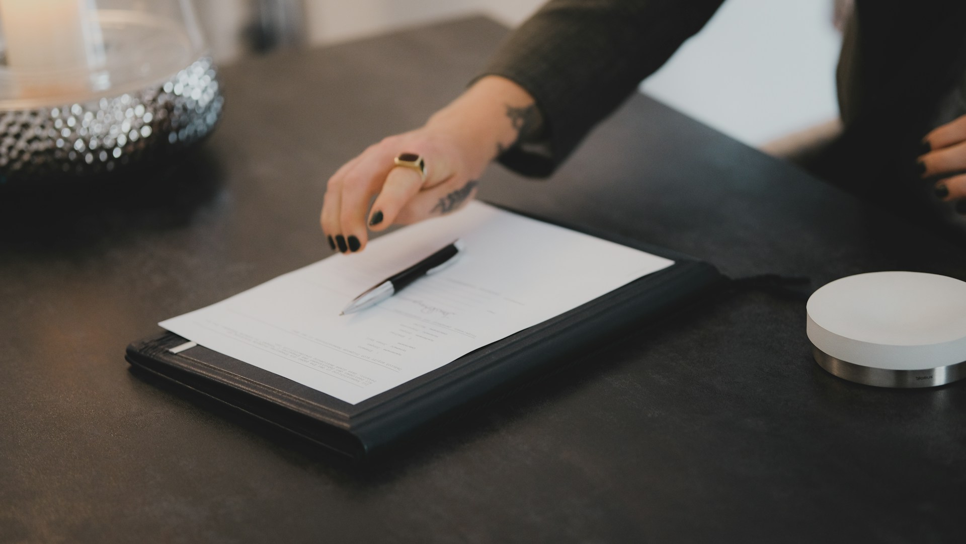 Hand signing a document on a dark desk, the moment a lease becomes binding.