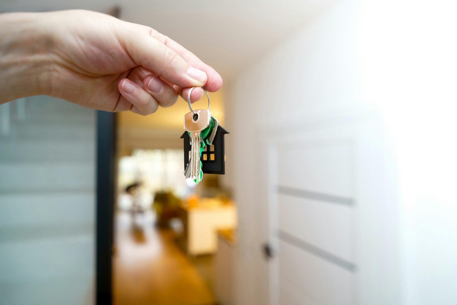 Hand holding out apartment keys at the door, the moment a new lease starts.