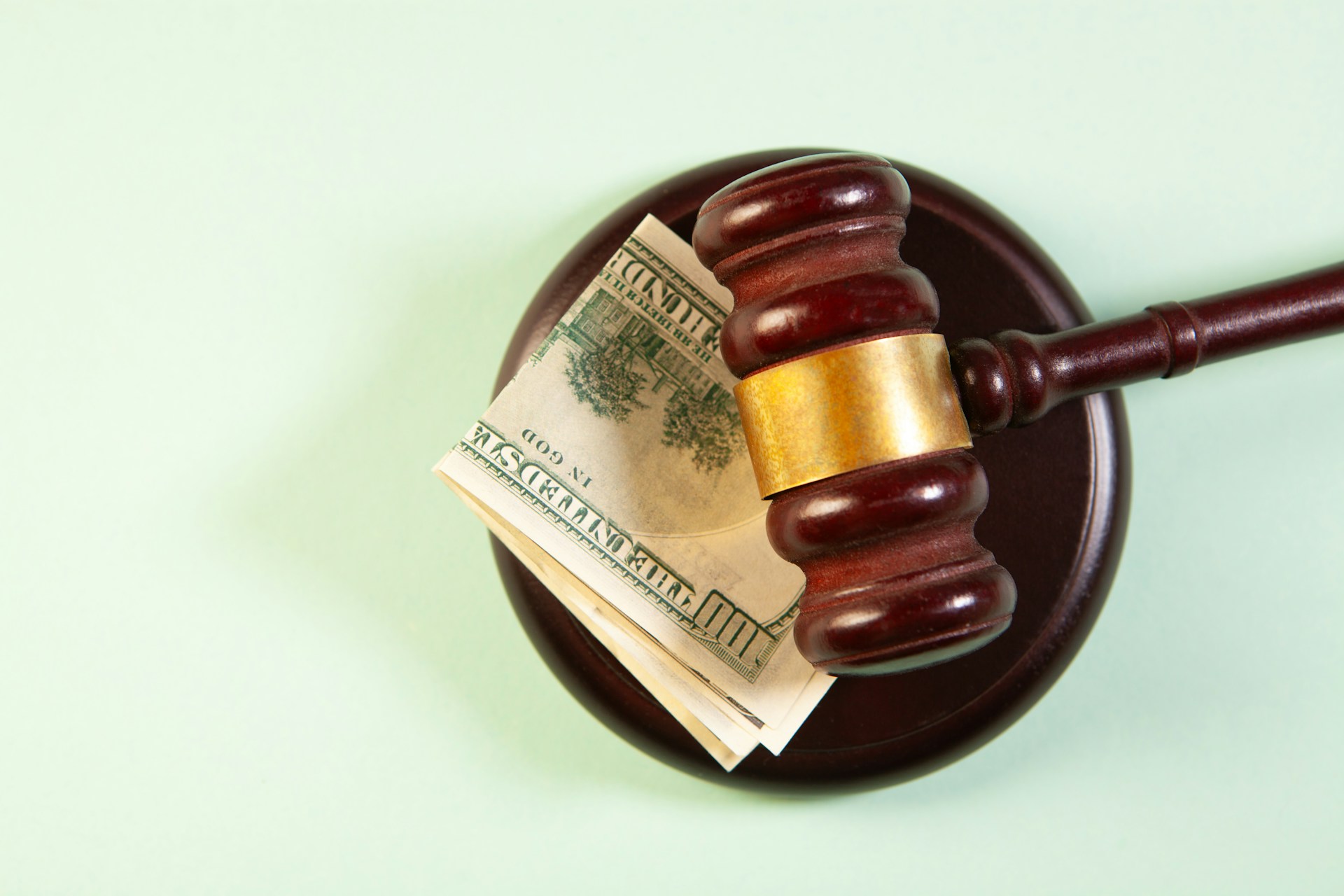 Wooden gavel and stack of currency notes on white background, symbolizing legal and financial matters.